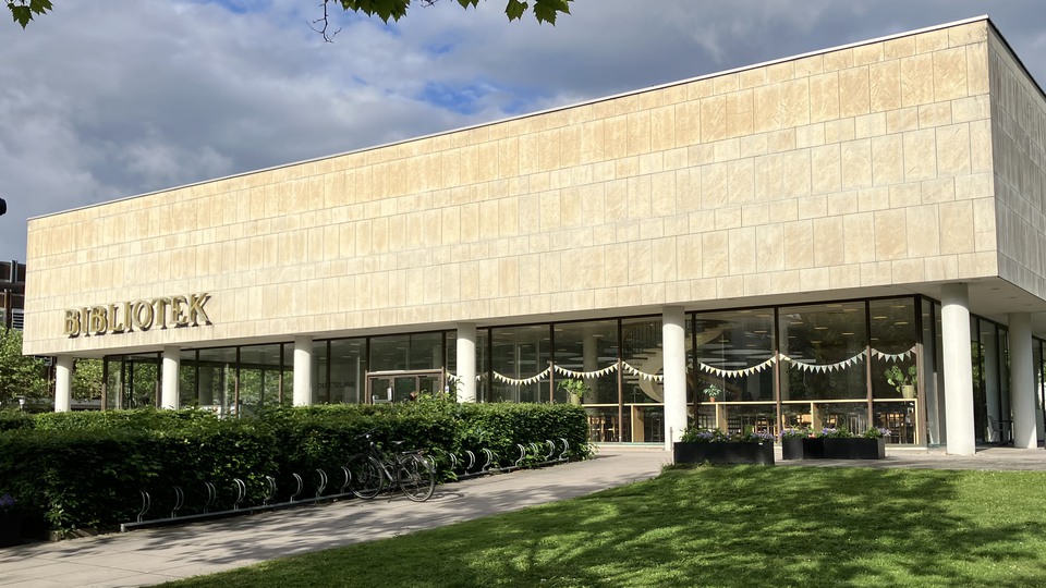 Ingen till Växjö bibliotek med grusgång, häck och ingången i bakgrunden. 