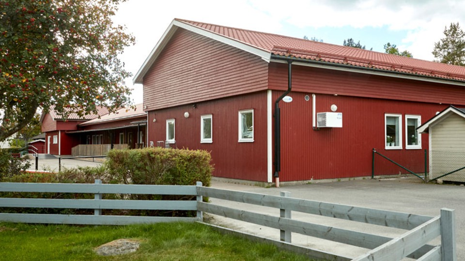 Röd träbyggnad, framför byggnaden är det ett trästaket.